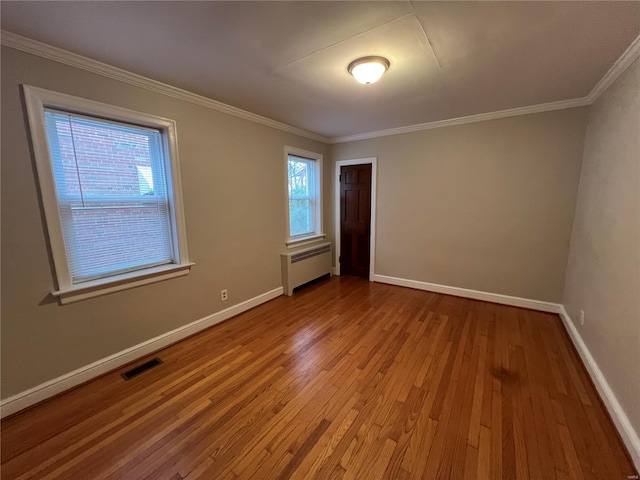 spare room with a wealth of natural light, radiator heating unit, and light wood-type flooring