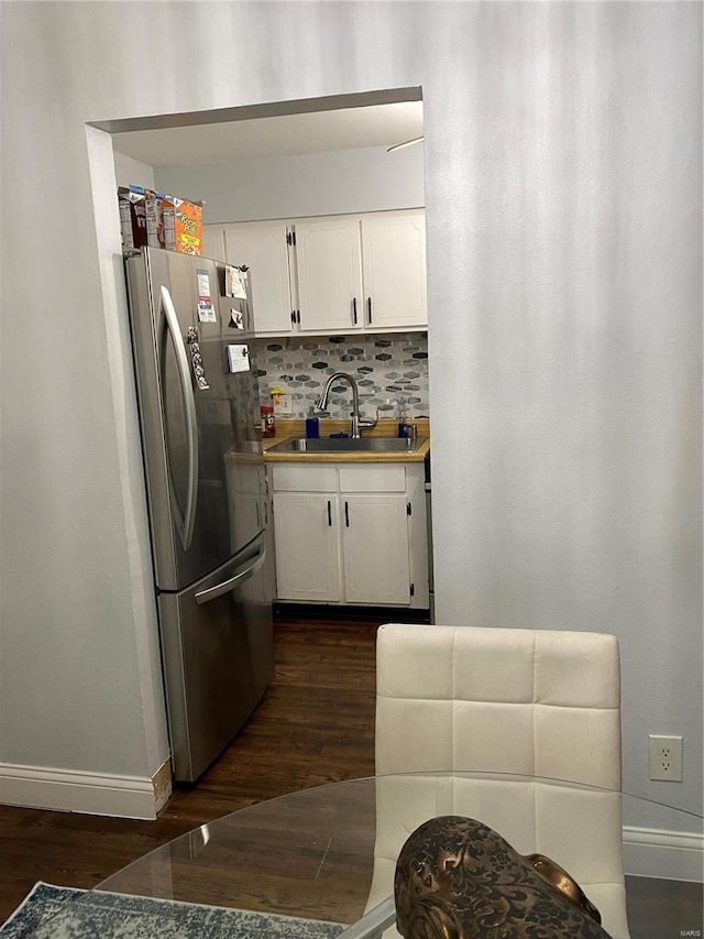 kitchen with stainless steel fridge, dark hardwood / wood-style flooring, backsplash, sink, and white cabinetry