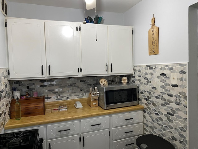 kitchen featuring tasteful backsplash, white cabinets, and black gas range oven