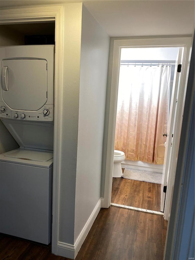 laundry area featuring dark hardwood / wood-style floors and stacked washer / dryer