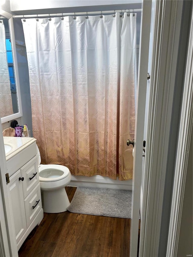 full bathroom with shower / bath combo with shower curtain, vanity, wood-type flooring, and toilet