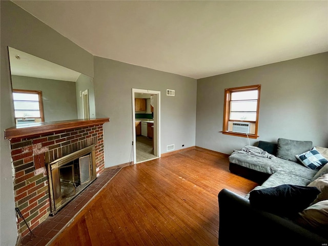 living room with wood-type flooring, a fireplace, and a wealth of natural light