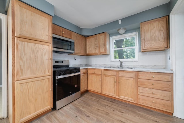 kitchen featuring decorative backsplash, appliances with stainless steel finishes, sink, light brown cabinets, and light hardwood / wood-style floors