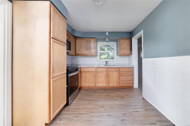 kitchen with light brown cabinetry, light wood-type flooring, stainless steel appliances, and sink