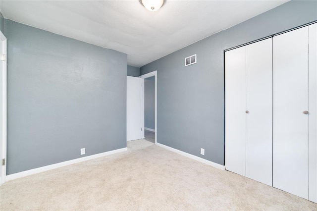 unfurnished bedroom with light carpet and a closet