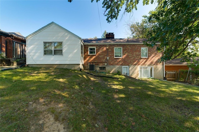 rear view of house with central air condition unit and a lawn