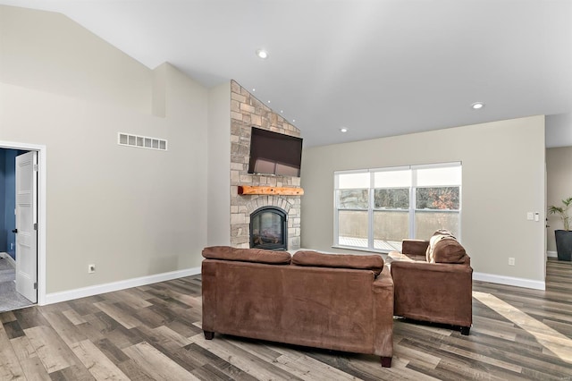 living room featuring wood-type flooring, high vaulted ceiling, and a stone fireplace