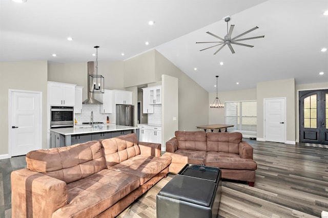 living room with light wood-type flooring, high vaulted ceiling, ceiling fan, and sink