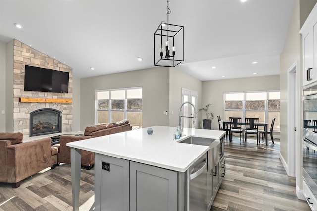 kitchen featuring dishwasher, a fireplace, a healthy amount of sunlight, and an island with sink