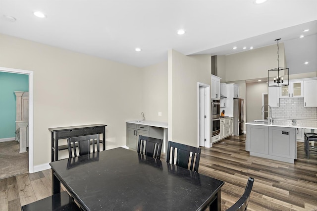 dining area featuring a chandelier, sink, and dark wood-type flooring