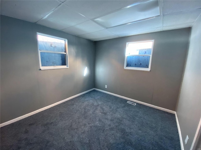 spare room with a drop ceiling and dark carpet