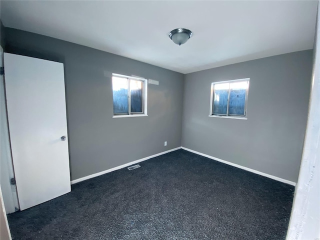 spare room with dark colored carpet