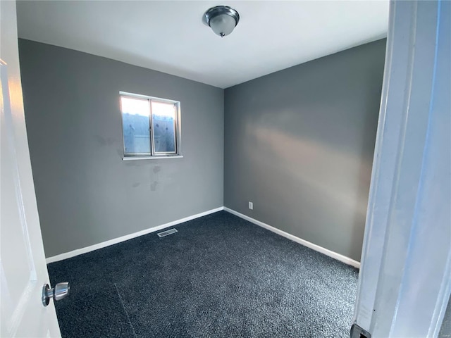 spare room with dark colored carpet