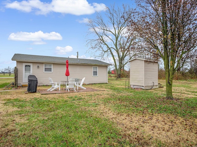 rear view of property with a yard, a fire pit, and a storage unit