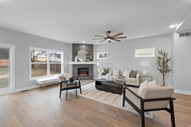 living room with ceiling fan, a fireplace, and light wood-type flooring