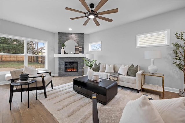 living room featuring a fireplace, light hardwood / wood-style flooring, and ceiling fan