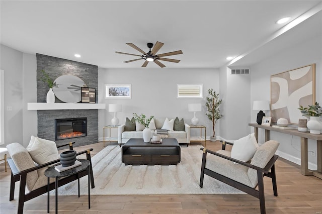 living room with a fireplace, light hardwood / wood-style flooring, and ceiling fan