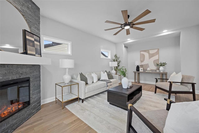 living room with a fireplace, light hardwood / wood-style floors, and ceiling fan