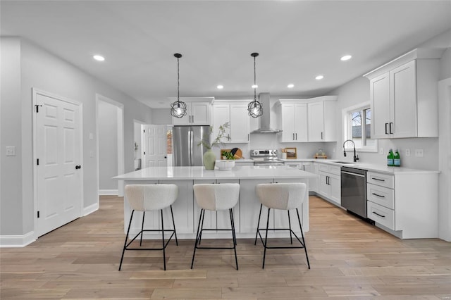 kitchen with wall chimney exhaust hood, a kitchen island, decorative light fixtures, and appliances with stainless steel finishes