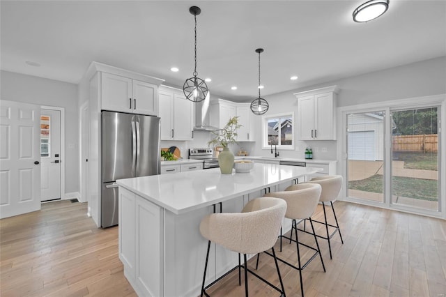 kitchen featuring white cabinets, wall chimney exhaust hood, a center island, and stainless steel appliances