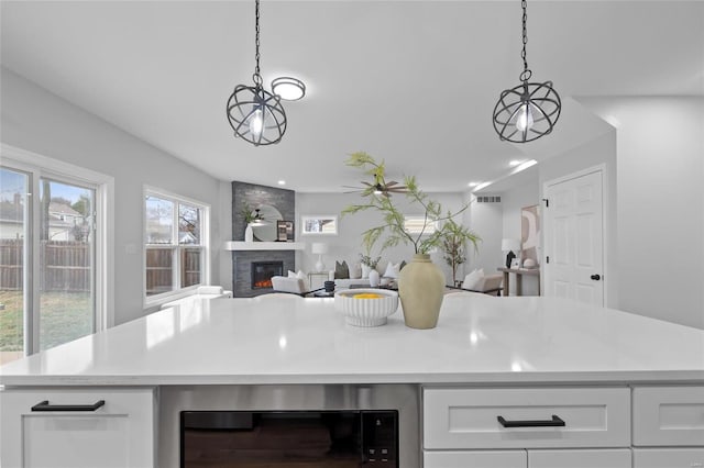 kitchen with white cabinets, decorative light fixtures, a fireplace, and beverage cooler