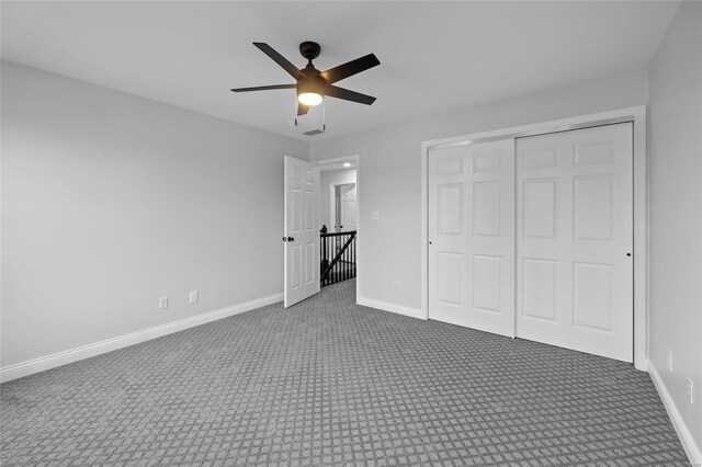 unfurnished bedroom featuring ceiling fan, a closet, and dark carpet