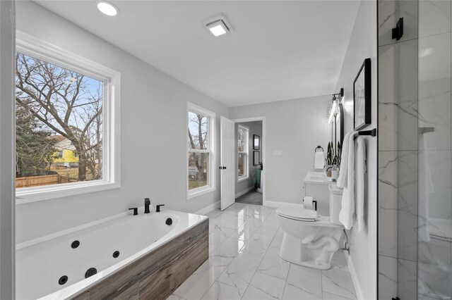 bathroom featuring a washtub, a healthy amount of sunlight, and toilet