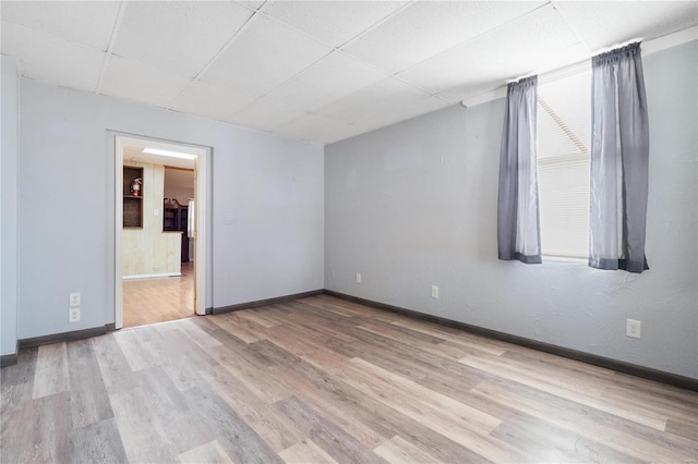 unfurnished room featuring a drop ceiling and light wood-type flooring