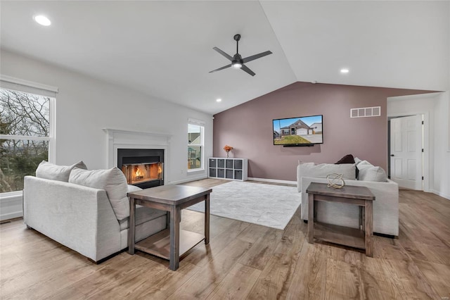 living room with light hardwood / wood-style floors, ceiling fan, and lofted ceiling