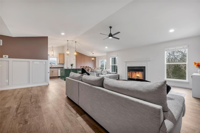 living room featuring light hardwood / wood-style floors, ceiling fan, and lofted ceiling