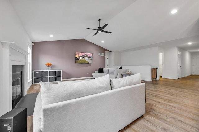 living room featuring ceiling fan, light hardwood / wood-style floors, and vaulted ceiling