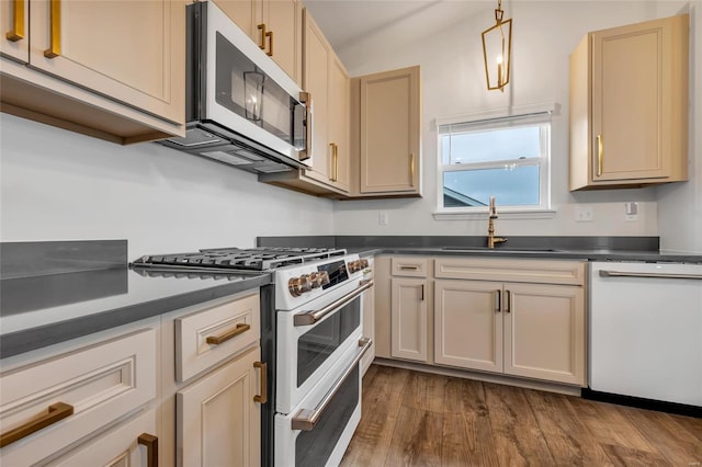 kitchen featuring sink, pendant lighting, white appliances, and hardwood / wood-style flooring