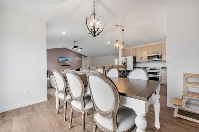 dining area featuring ceiling fan with notable chandelier, light hardwood / wood-style floors, and vaulted ceiling