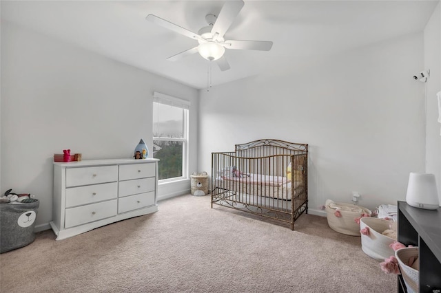 bedroom featuring ceiling fan, light carpet, and a nursery area