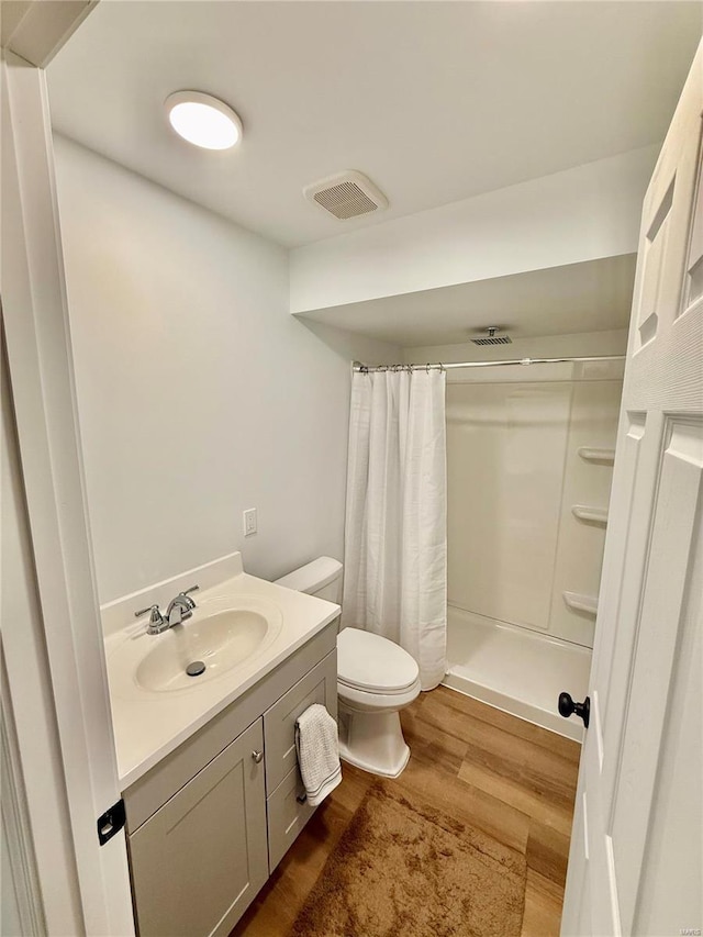 bathroom featuring a shower with curtain, toilet, vanity, and hardwood / wood-style flooring