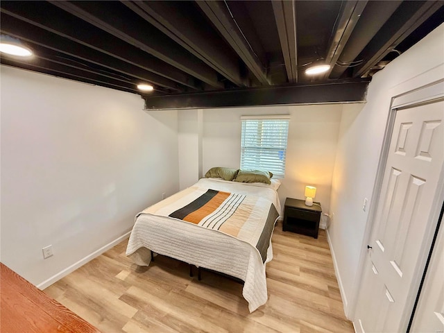 bedroom featuring beam ceiling and light wood-type flooring