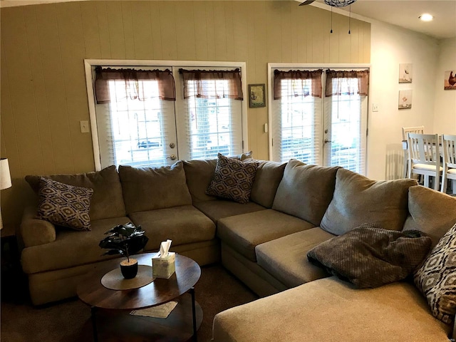 living room with ceiling fan, lofted ceiling, and wood walls