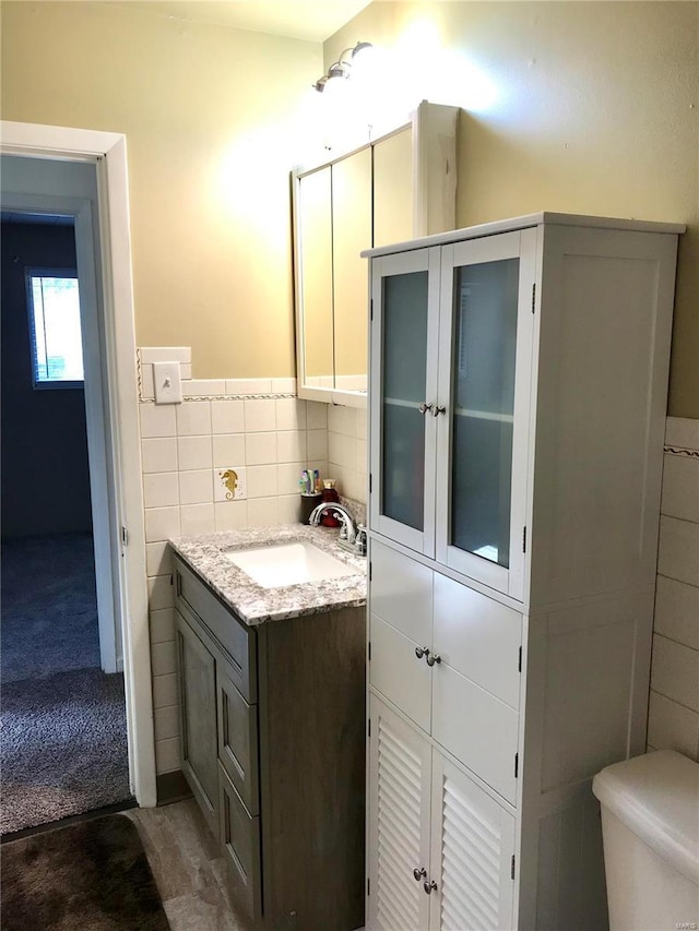 bathroom featuring vanity, toilet, and tile walls