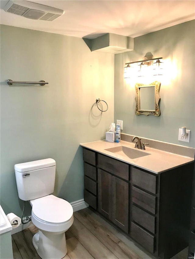 bathroom featuring vanity, wood-type flooring, and toilet