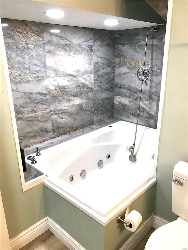 bathroom with hardwood / wood-style flooring, tiled shower / bath combo, and toilet