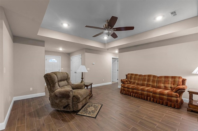 living room featuring hardwood / wood-style floors, a tray ceiling, and ceiling fan