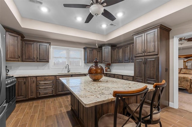 kitchen with gas stove, sink, a kitchen breakfast bar, dark hardwood / wood-style floors, and a kitchen island