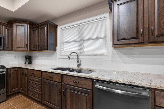 kitchen with backsplash, dark brown cabinetry, stainless steel appliances, sink, and light hardwood / wood-style flooring