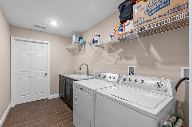 washroom featuring washer and dryer, dark hardwood / wood-style floors, cabinets, and sink