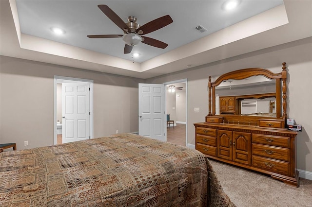 bedroom with ceiling fan, light carpet, and a tray ceiling