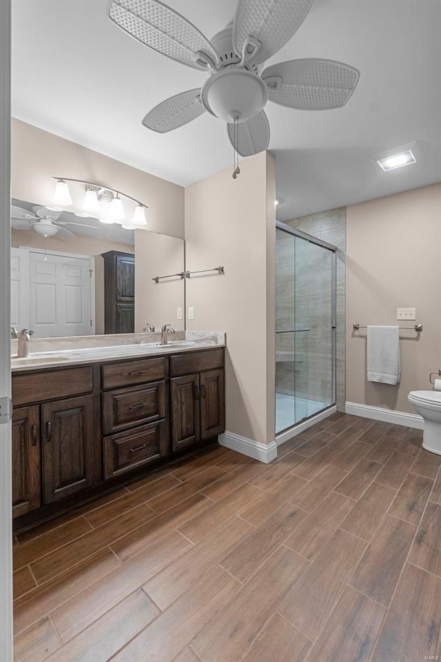 bathroom with ceiling fan, vanity, a shower with shower door, and toilet