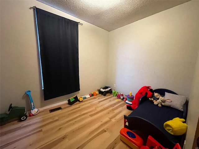 rec room featuring wood-type flooring and a textured ceiling