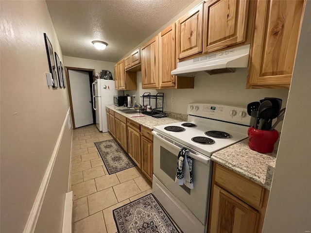 kitchen featuring light stone counters, a textured ceiling, white appliances, sink, and light tile patterned flooring