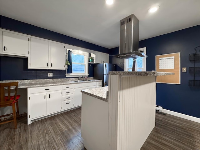 kitchen with white cabinetry, a kitchen island, stainless steel refrigerator, and range hood