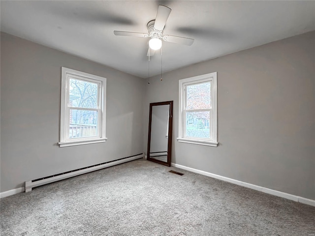 carpeted empty room featuring ceiling fan, a healthy amount of sunlight, and a baseboard radiator